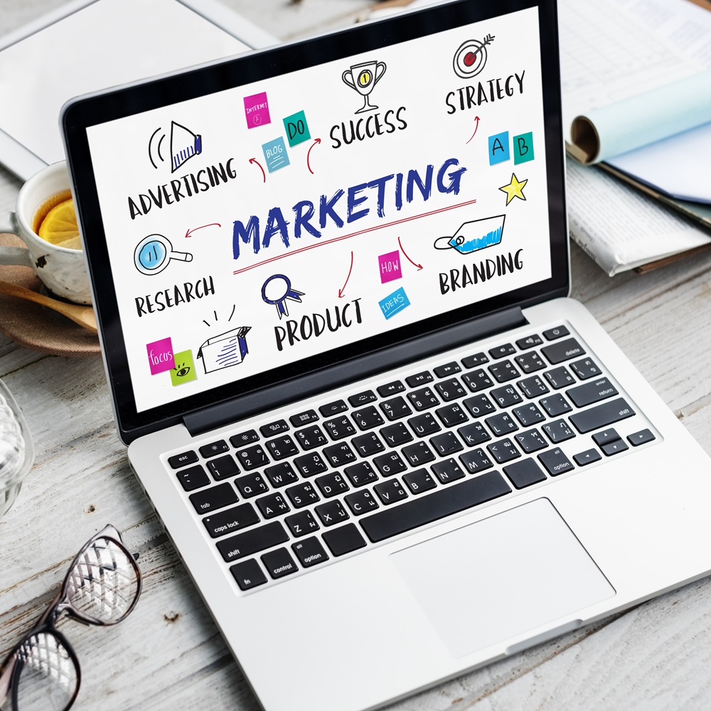 Open laptop displaying a colorful digital marketing diagram with words like advertising, strategy, product, and branding.
