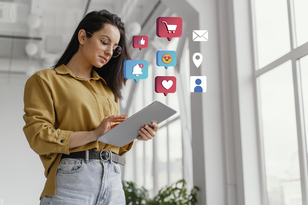Young woman using a tablet with social media icons like likes, comments, messages, and notifications floating around her.