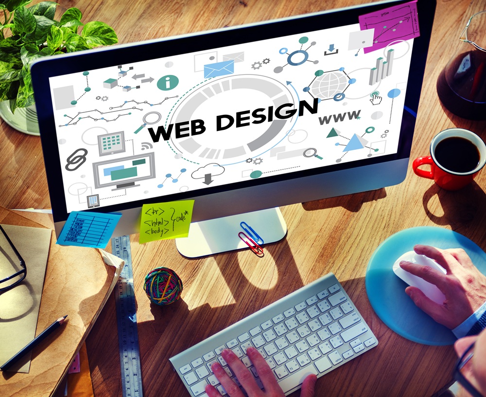 Person working at a desktop computer displaying the words “Web Design” surrounded by digital and creative icons.